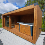 Nowoczesna całoroczna sauna ogrodowa o wymiarach 6 x 2,5 m połączona z zadaszoną strefą relaksu, wbudowanym jacuzzi oraz banią do morsowania